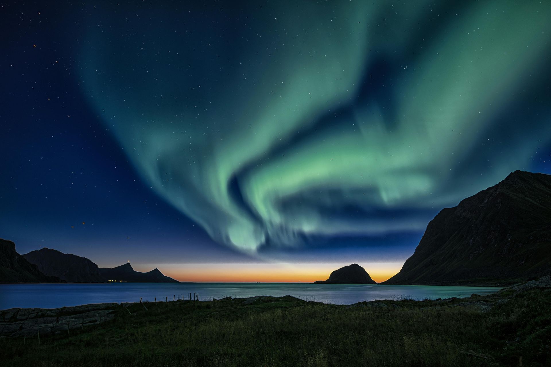 Breathtaking view of the Northern Lights illuminating the Lofoten Islands in Norway at twilight.